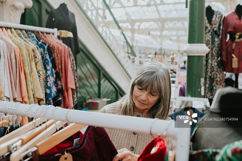 一位成熟的女性在阳光明媚的室内市场购买衣物图片素材
