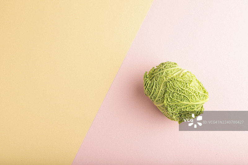 粉橙色柔和纸张背景上的绿色生菜。俯视，留白，平面布置。健康食品，蔬菜，极简主义。图片素材