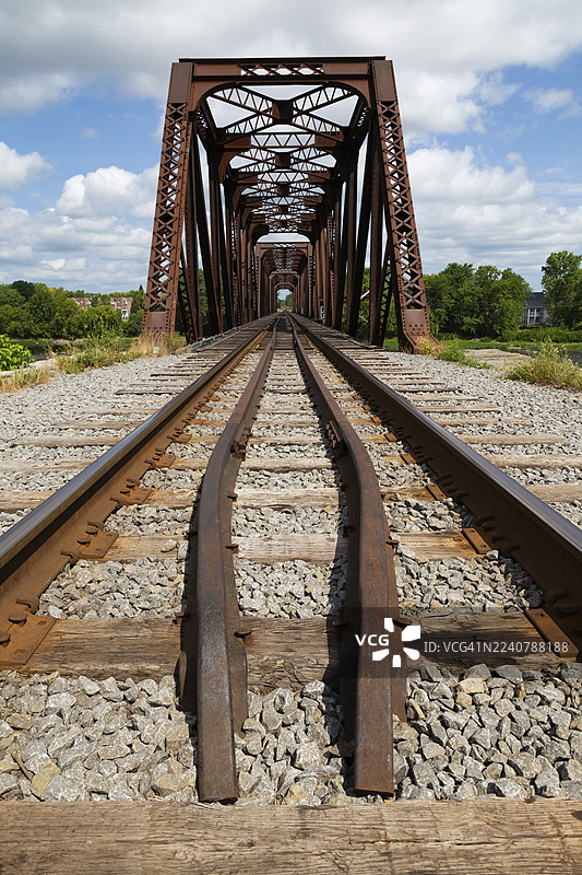 夏日,加拿大魁北克省拉瓦尔市,铁轨通向泰尔伯恩普拉特桁架老式生锈的铁路桥,该桥横跨圣伊莱尔河(Des Mille-Iles River)。图片素材