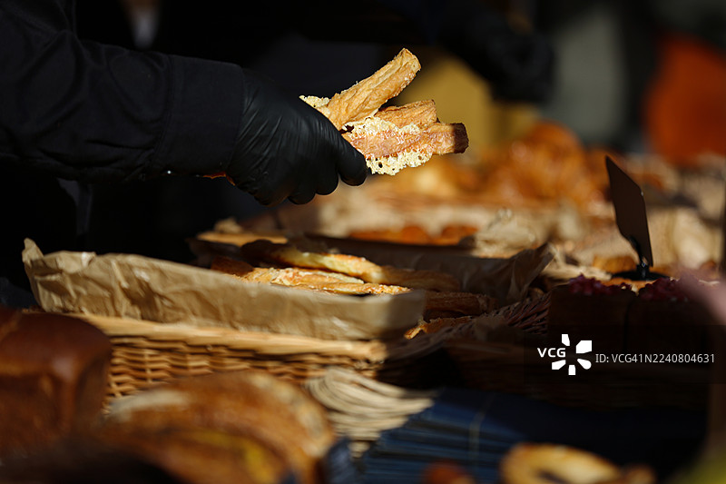 街边咖啡馆里，烘焙师的手将新鲜的烤面包棍装进棕色纸午餐袋里，特写镜头。图片素材