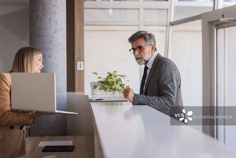 商务人士向持有笔记本电脑的前台抱怨图片素材