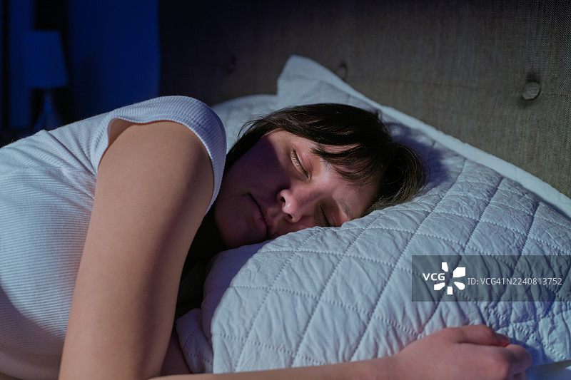 女人在夜晚舒适的床上安然入睡图片素材