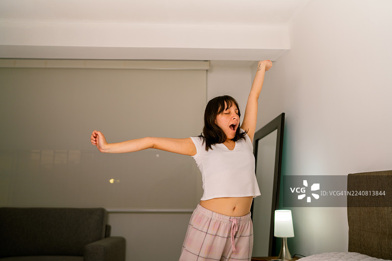 女人醒来后在床上打哈欠伸懒腰图片素材