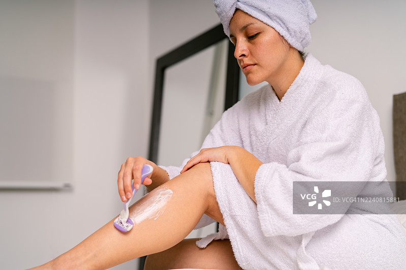 女子刮腿毛，保持晨间美容习惯图片素材
