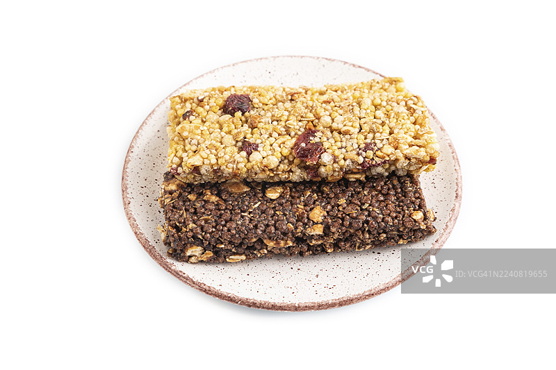 焦糖、坚果和谷物脆片格兰诺拉麦片棒，放在陶瓷盘中，孤立在白色背景上。侧视图，特写。图片素材