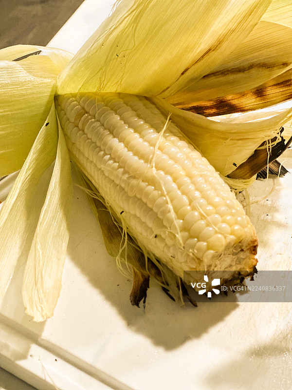烤玉米特写，玉米壳被剥开露出白色的玉米粒图片素材