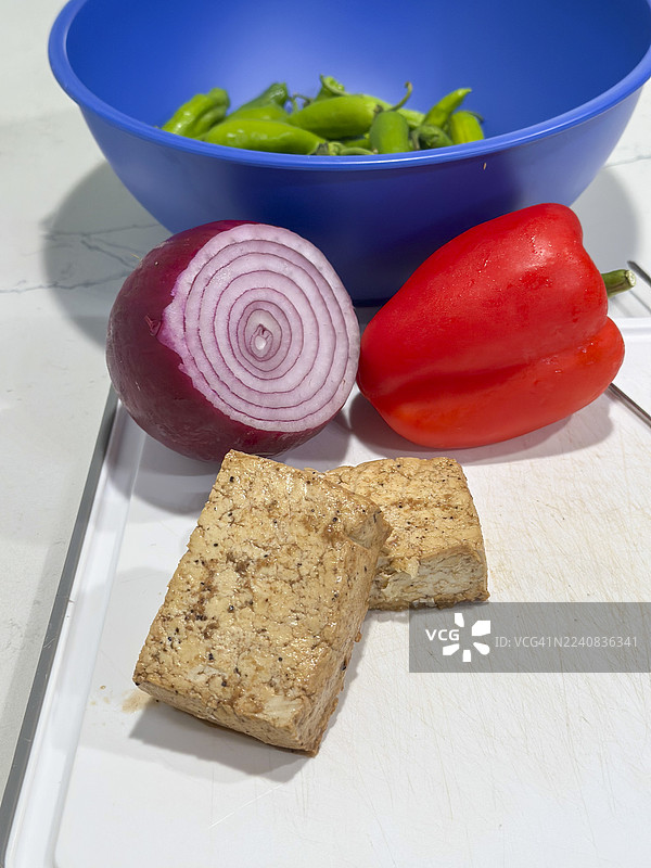 准备蔬菜和腌制豆腐来制作烤串，在烤架上烹饪；红椒、豆腐和紫洋葱、青椒；系列的一部分图片素材
