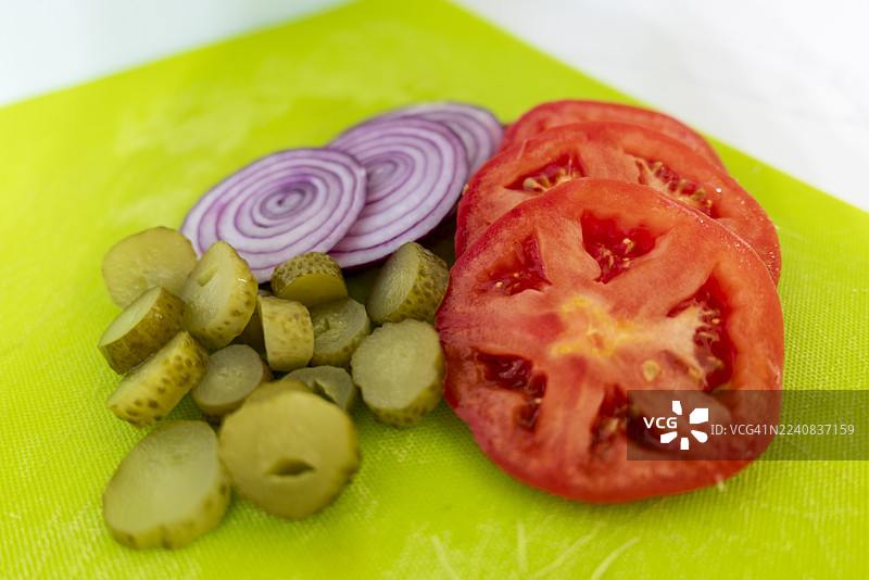 烤架上户外烹饪的汉堡切片蔬菜 - 传家宝番茄、紫洋葱和莳萝泡菜；系列的一部分图片素材