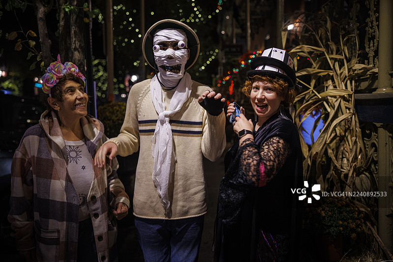 三代同堂，与患有自闭症、身着木乃伊服装的青少年一起庆祝万圣节。夜晚的户外聚会，装饰节日化。图片素材