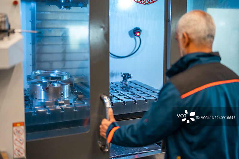 成熟的西班牙裔数控操作员在工程车间操作机械图片素材