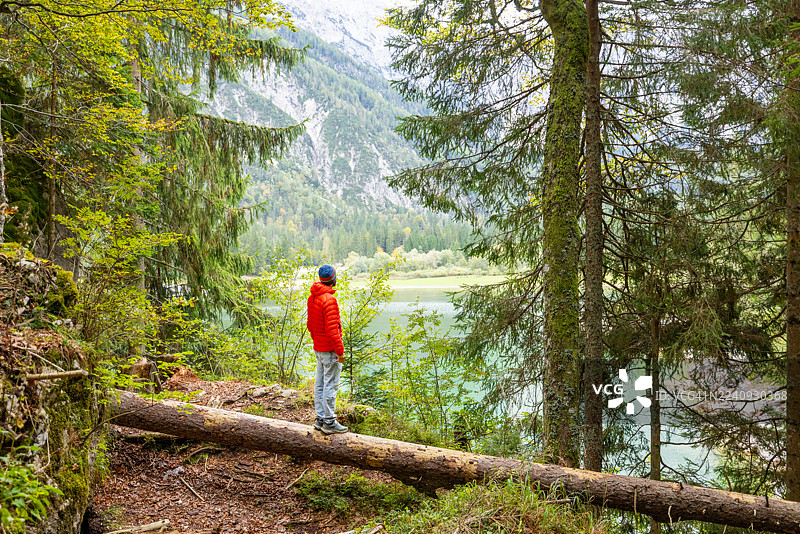 男人站在原木上眺望山间湖泊图片素材