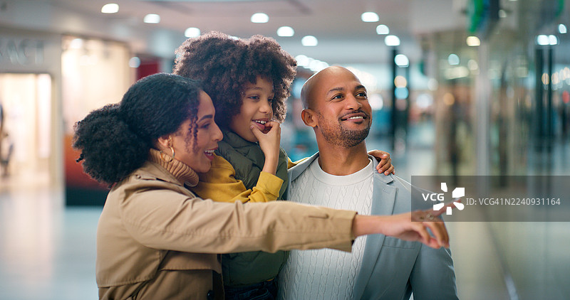 父母、孩子在商场窗边购物，对商品感兴趣，画面有景深效果。黑人家庭和孩子在店里探索，选择零售商品并享受购物时光。图片素材