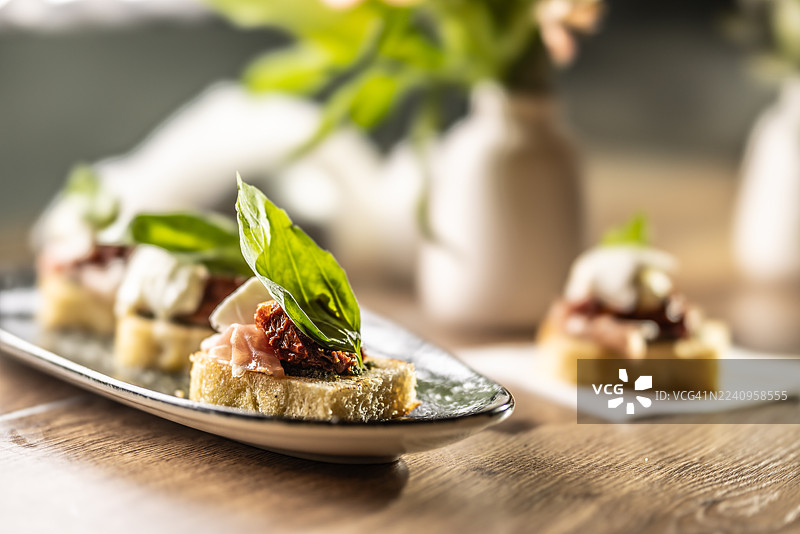 长方形盘子里的佛卡夏，配有番茄干、意大利熏火腿和罗勒叶，作为餐厅开胃菜。图片素材