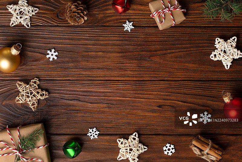 圣诞节背景，构图中心留有复制空间，圣诞礼物盒用棕色牛皮纸包装，星形装饰、圣诞饰品和松树枝在乡村木质背景上。图片素材