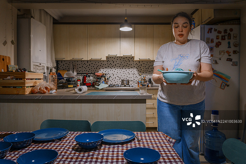 女子在家准备家庭晚餐，正在端上食物图片素材