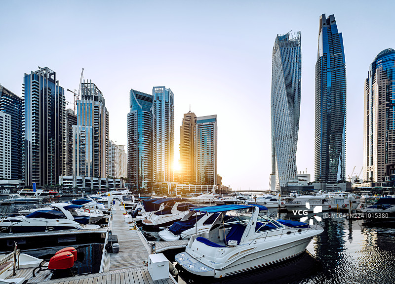 日落时分，迪拜码头天际线映衬着豪华游艇和现代摩天大楼。图片素材