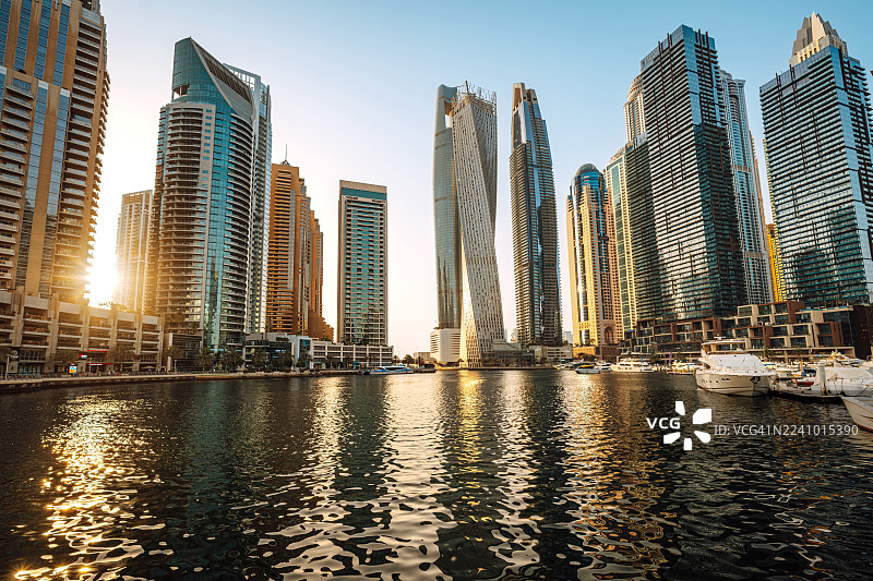 日落时分，迪拜码头天际线与现代摩天大楼倒映在水面上图片素材