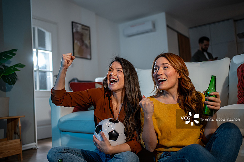 一群女性朋友在家观看足球比赛，庆祝胜利图片素材