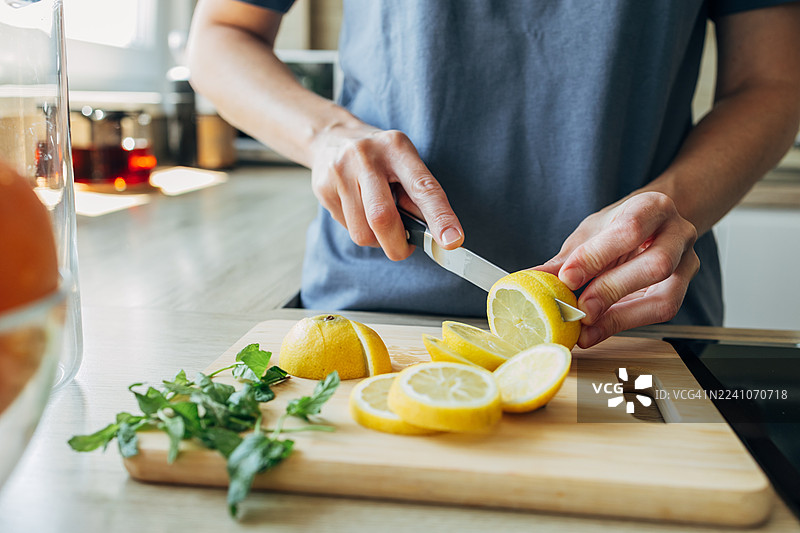 女子正在切新鲜柠檬制作健康的柑橘饮品图片素材