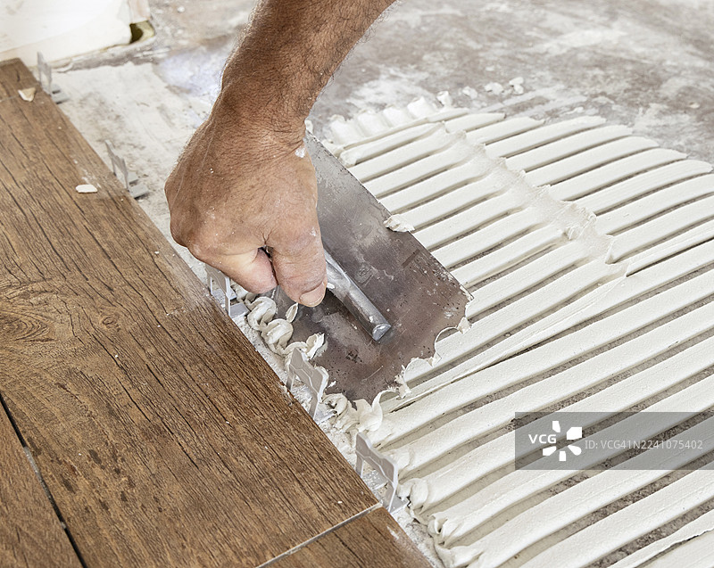 建筑工地上，工人正在铺设地砖的粘合剂的特写镜头图片素材