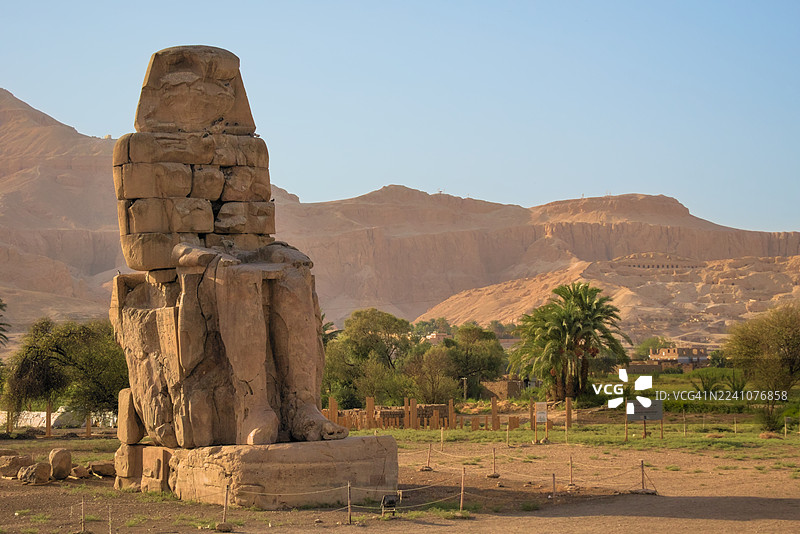 埃及卢克索，沙漠山脉与绿色田野映衬下的古门农巨像图片素材