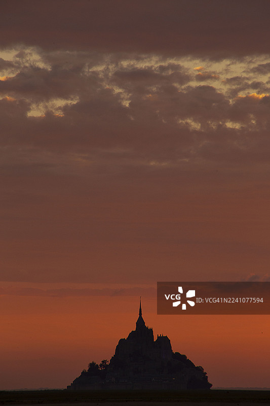 蒙圣米歇尔在充满活力的橙红色日落天空下的戏剧性剪影，唤起了历史和宏伟的感觉，法国芒什省图片素材