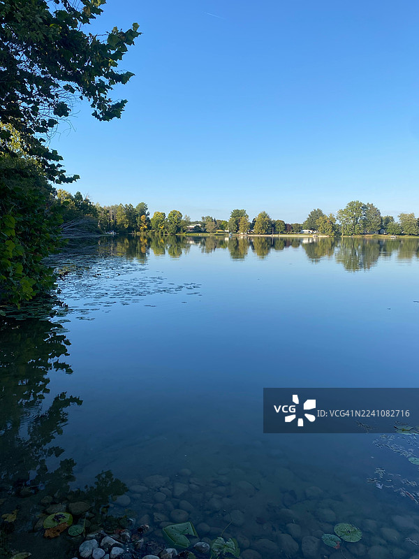 宁静的湖景，配以蔚蓝的天空和葱郁的绿色海岸线，美国，阿尔比恩图片素材