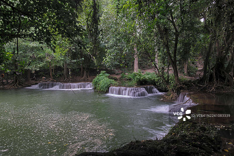 宁静的多层瀑布在茂密翠绿的森林中倾泻而下，营造出宁静的自然景观图片素材