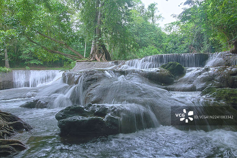郁郁葱葱的绿色森林中，美丽的层叠瀑布倾泻而下图片素材
