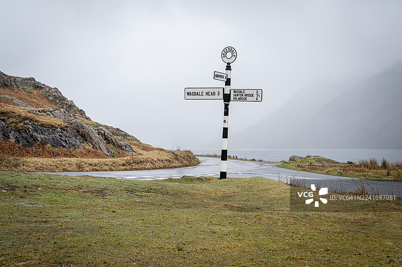 阴天时，路标指向湖区湖泊附近的各个地点图片素材