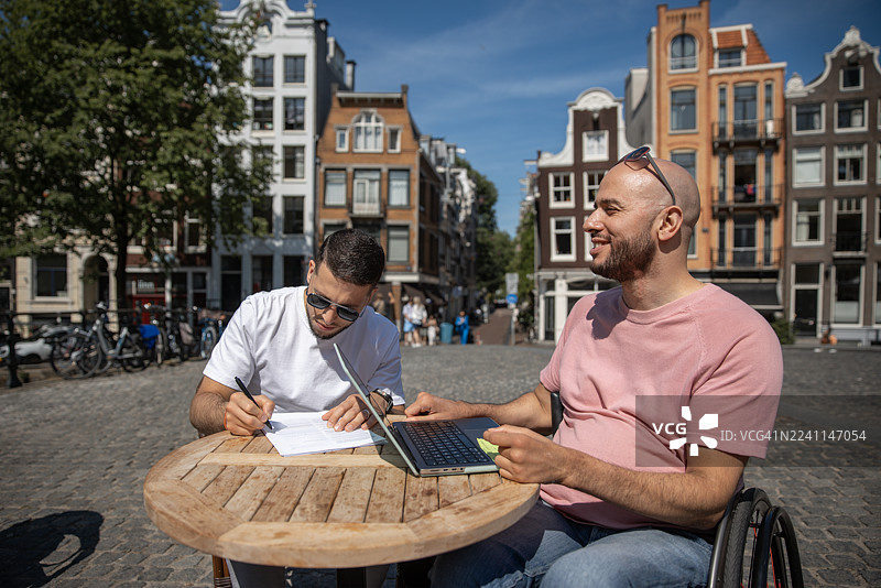 一位有残疾的英俊男子与他的兄弟在阿姆斯特丹进行城市旅游的一日游肖像图片素材