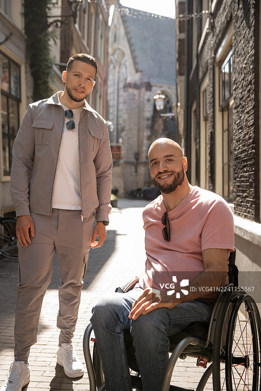 一位残疾的帅气男子与他的兄弟在阿姆斯特丹进行一次城市旅游。肖像照。图片素材