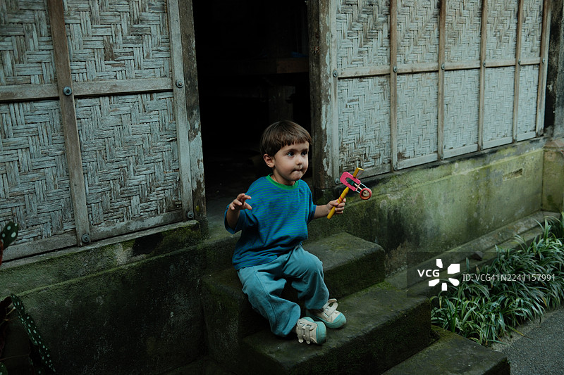 小男孩坐在台阶上玩玩具图片素材