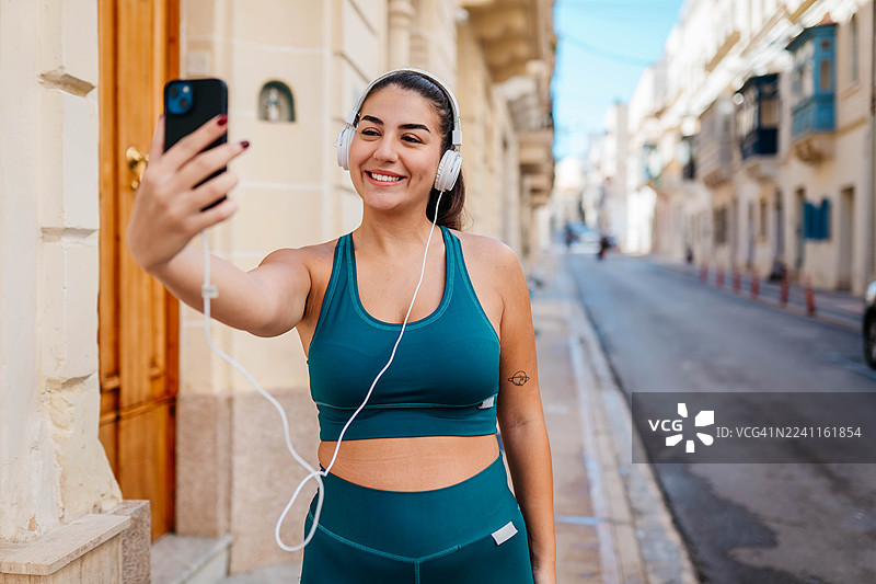 戴着耳机在城市中奔跑的女人图片素材