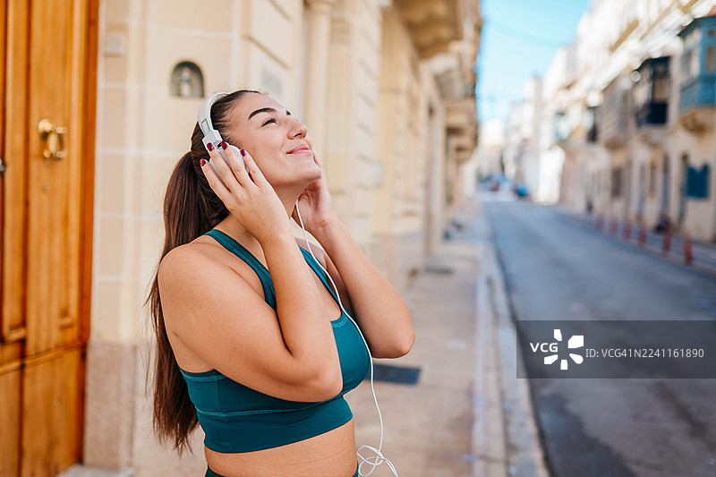 年轻女子在城市街道上跑步图片素材