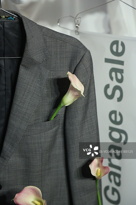 时尚灰色西装夹克上的旧货出售招牌，装饰着淡粉色马蹄莲花图片素材