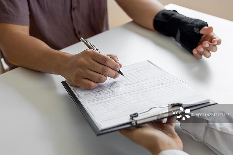 无法辨认的男性，手臂骨折，正在填写表格图片素材