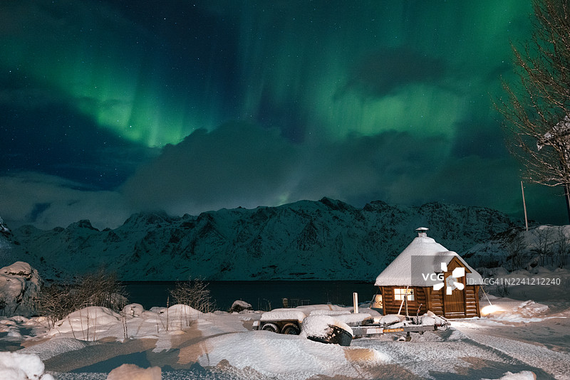罗弗敦群岛海边雪山上方，小屋内部温暖，北极光壮丽图片素材