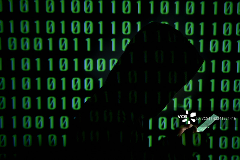 身穿连帽衫的男子使用智能手机，背景为二进制代码图片素材