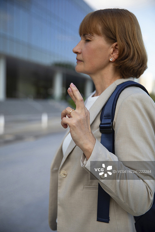 穿着西装外套，双手交叉站立的商界女性图片素材