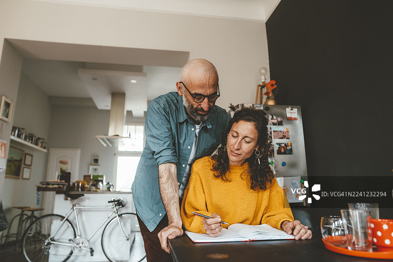 男子在家中帮助女子准备财务账单图片素材