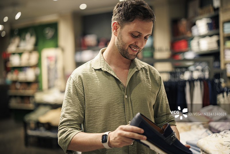 时尚商店里，一位男士微笑着选购鞋子图片素材