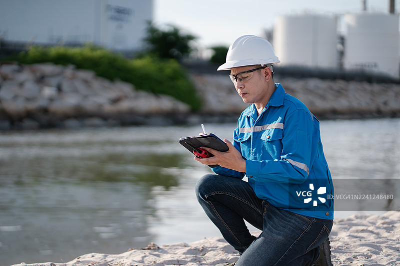 工厂检查工程师使用笔记本电脑在炼油厂和炼油厂进行检查，以检查工厂生产质量，以及能源生产的研发概念。图片素材