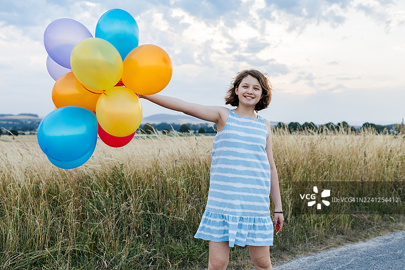 日落时分，女孩戴着心形太阳镜在户外开心地玩着气球。图片素材