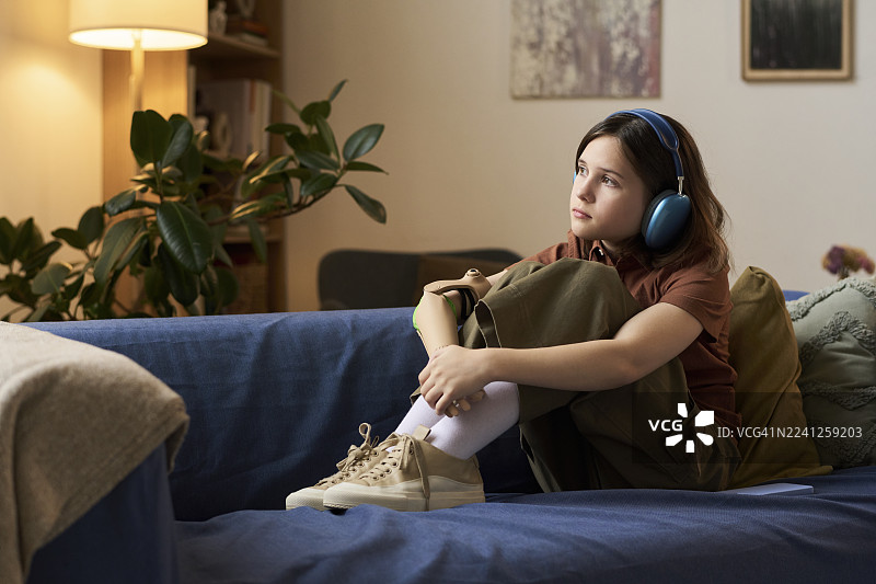 戴着耳机的女孩在家中放松，使用假肢图片素材