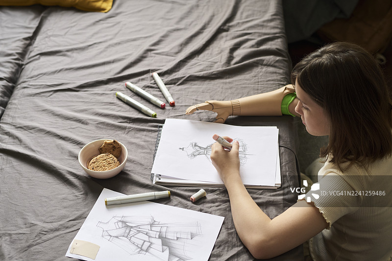 戴着假肢的创意女孩在卧室里绘制时装设计图图片素材