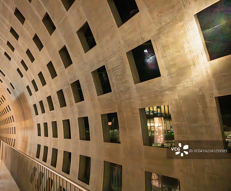 在机场的走廊里行走，墙壁上有许多小方窗，让光线透入。图片素材