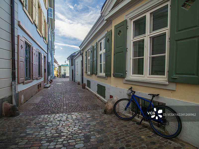 瑞士巴塞尔城市州巴塞尔老城中，中世纪风格的莱茵跳蚤鹅卵石步行小巷的景观，这里有巴洛克风格的建筑、色彩缤纷的百叶窗和格子窗户的房屋，以及一辆靠墙放置的自行车。图片素材