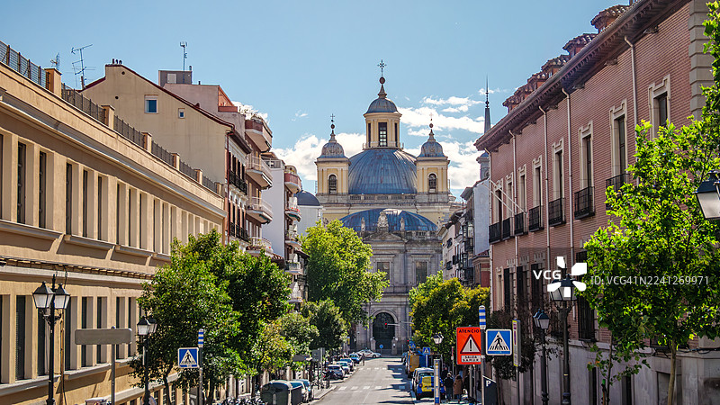 从马德里拉拉蒂纳区一条空旷街道的尽头望去,圣弗朗西斯科大教堂(Real Basilica de San Francisco El Grande)的立面和圆顶的视角,这座18世纪的新古典主义建筑被列为保护建筑。图片素材