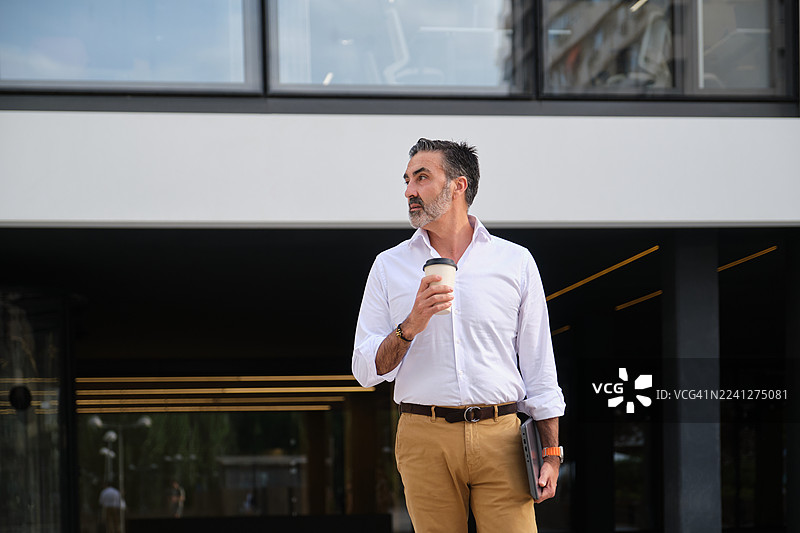 穿着西装的商人在办公楼外喝咖啡休息图片素材